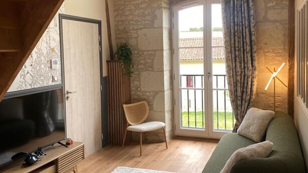 Un salon confortable avec un canapé, un fauteuil, un téléviseur et un escalier.