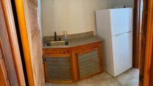 Eine kleine Küche mit Spüle, Kühlschrank und Holzschränken.