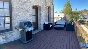 Ein Balkon mit einem Steinhaus, einem Grill und Gartenmöbeln.