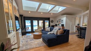 Un salon spacieux avec un canapé bleu foncé, un plancher en bois et des fenêtres de toit.