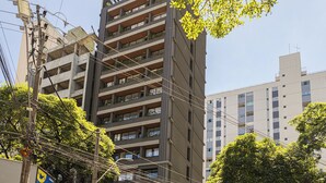 Un immeuble à plusieurs étages doté de balcons, entouré d’arbres et de lignes électriques.