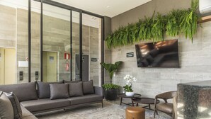 Un hall d’entrée moderne avec un canapé gris, une table basse et une plante en pot.