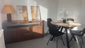 Et spiseområde med et rundt træbord, sorte stole, en lampe og dekorative paneler.