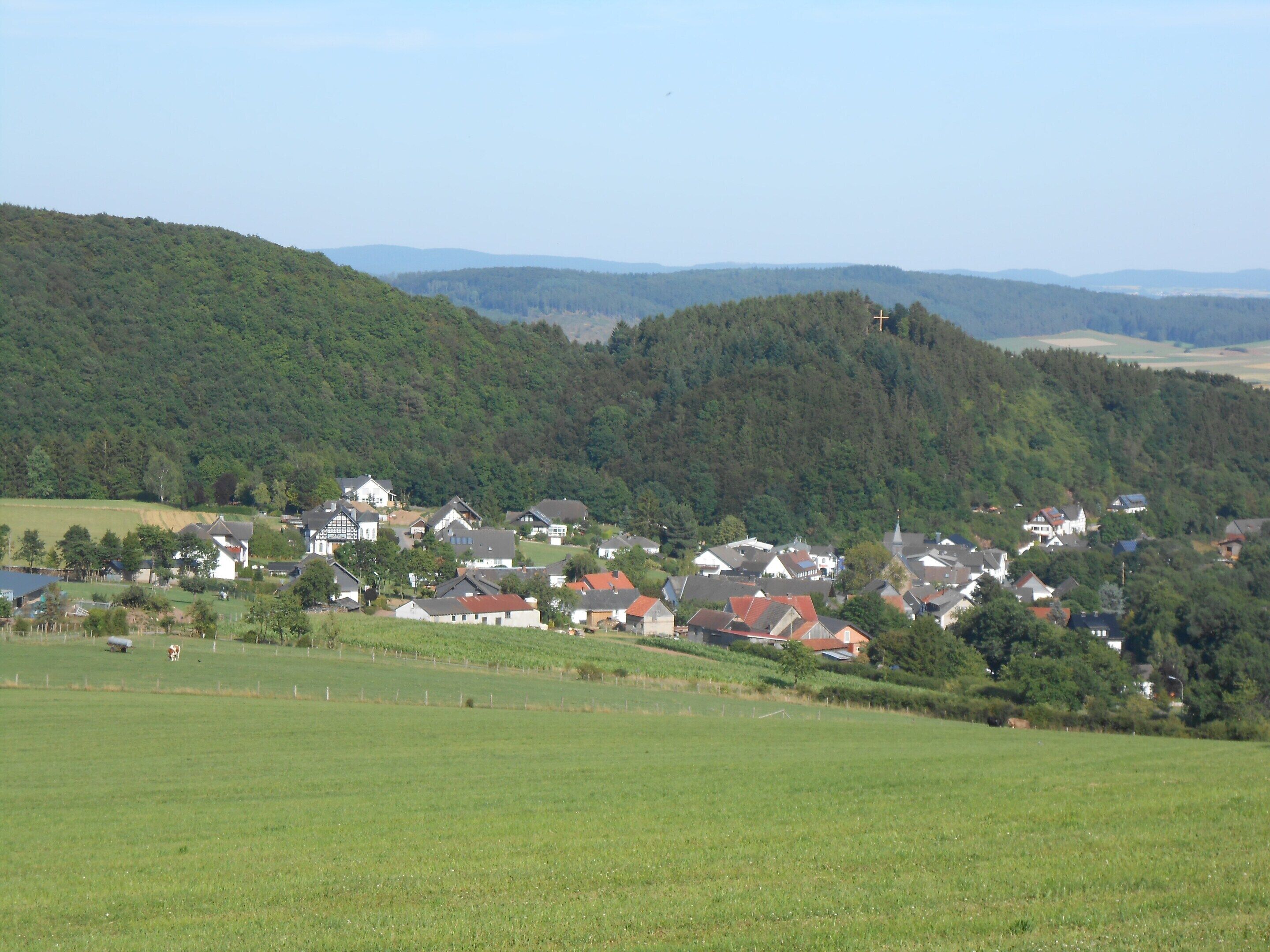 Un pueblo rural con casas rodeadas de campos verdes y colinas.
