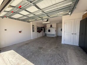 Eine geräumige Garage mit Betonboden, Metalldach und einer weißen Tür rechts.