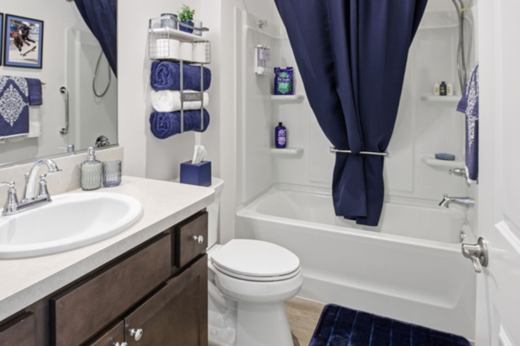 A bathroom with a white sink, a toilet, and a bathtub. There are towels and toiletries on shelves.