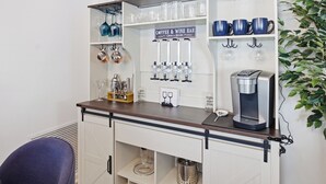 Et område med bar, kaffemaskine, vinglas og et skilt, der angiver at det er en døgnåben kaffe- og vinbar.