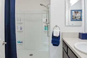 Ein Badezimmer mit Dusche, Waschbecken und Handtuchhalter.
