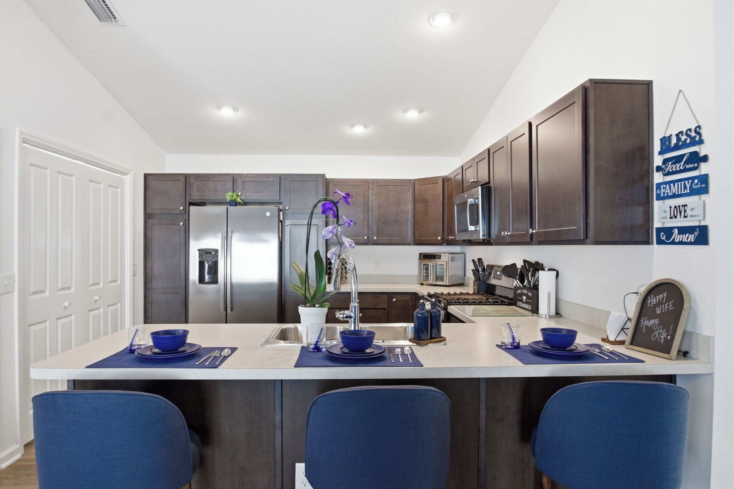 A modern kitchen with a central island, stainless steel appliances, and dark wood cabinets.