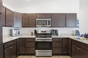 A kitchen with dark wood cabinets, a stainless steel microwave, a built-in oven, and a gas stove. - The Villages Rental - Golf Cart - Fenced Yard - Large Dogs - Brownwood (The Villages)