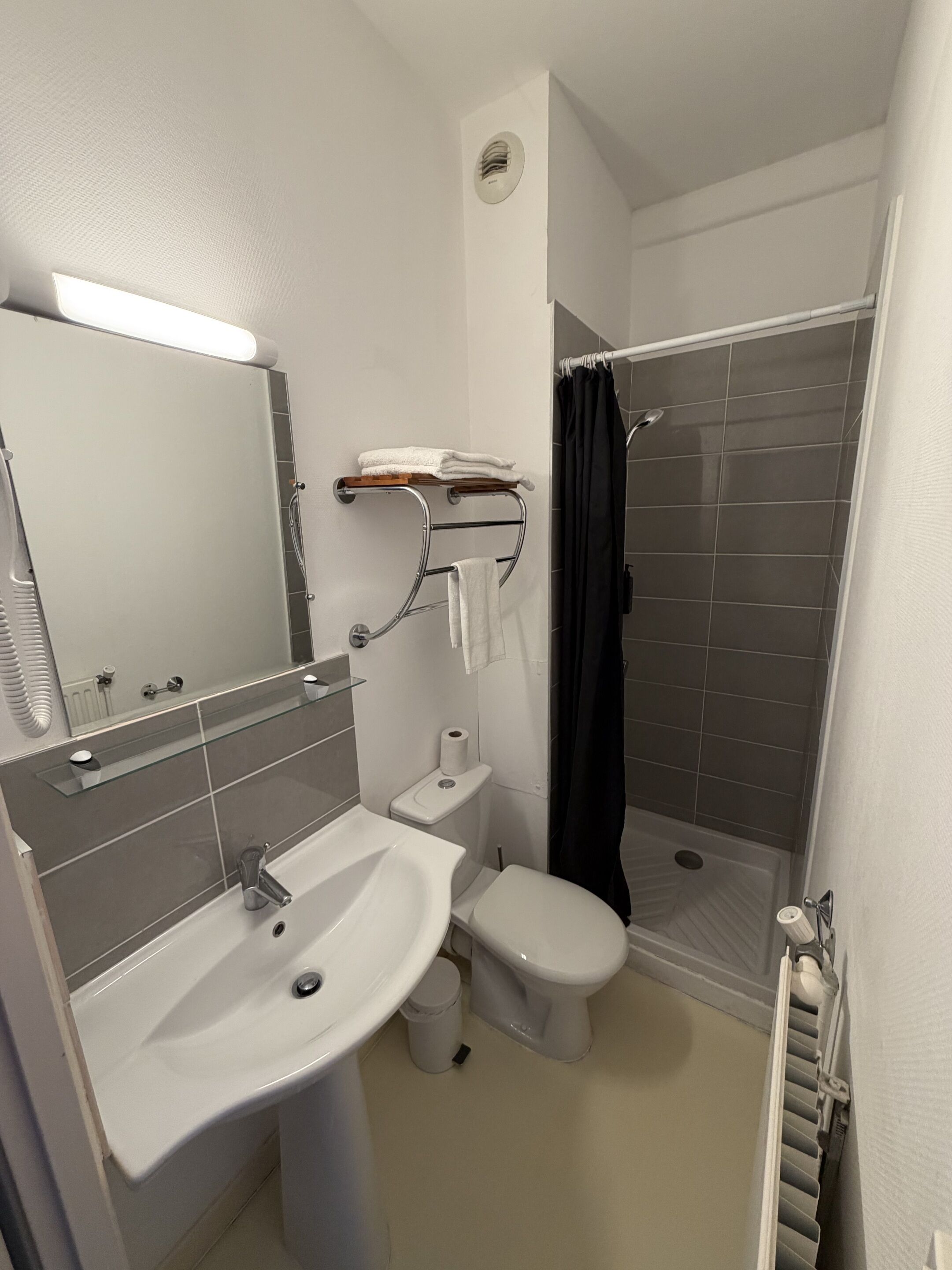A modern bathroom with a white sink, toilet, and shower.