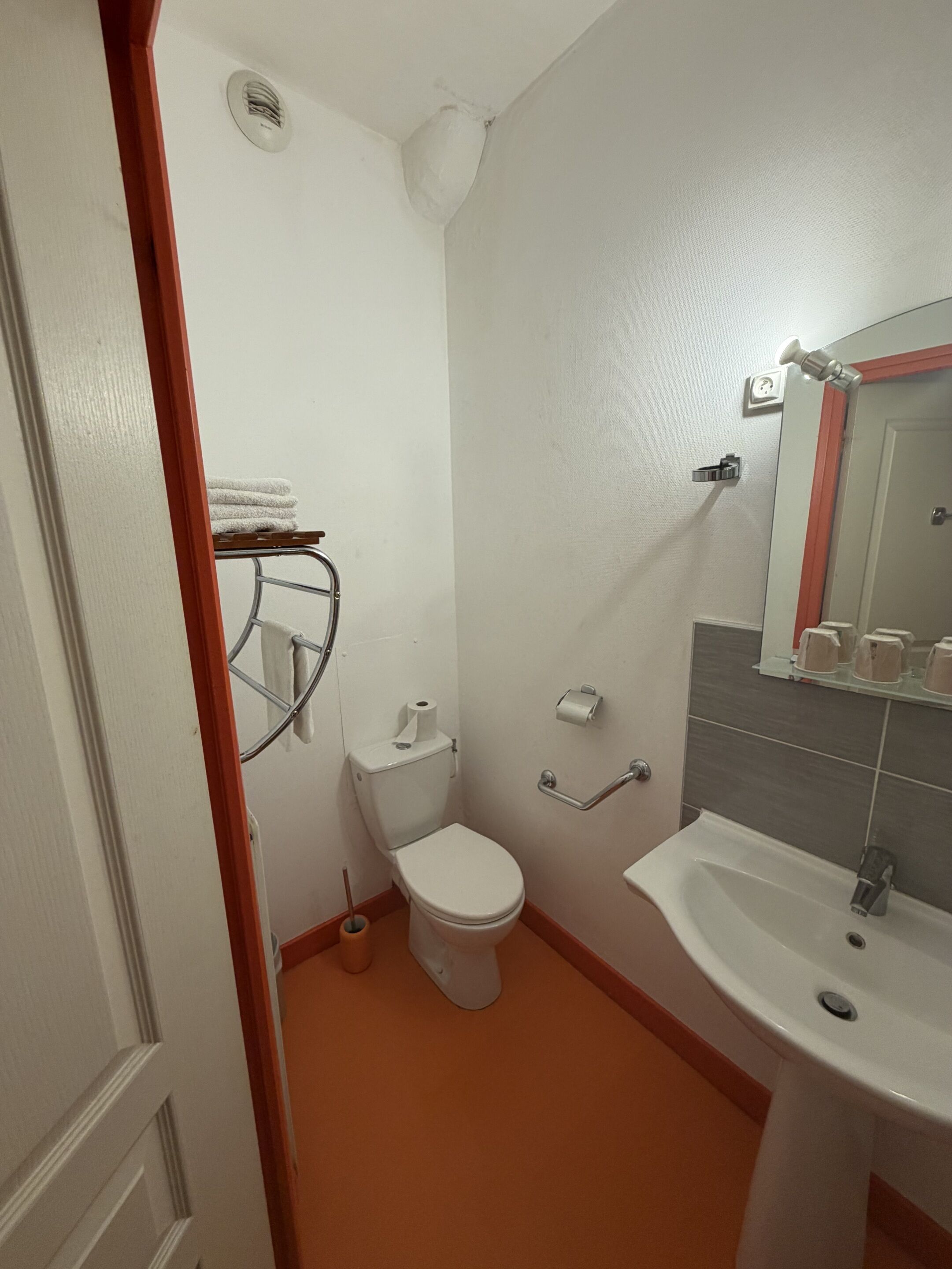 A small bathroom with a toilet, sink, and towel rack.