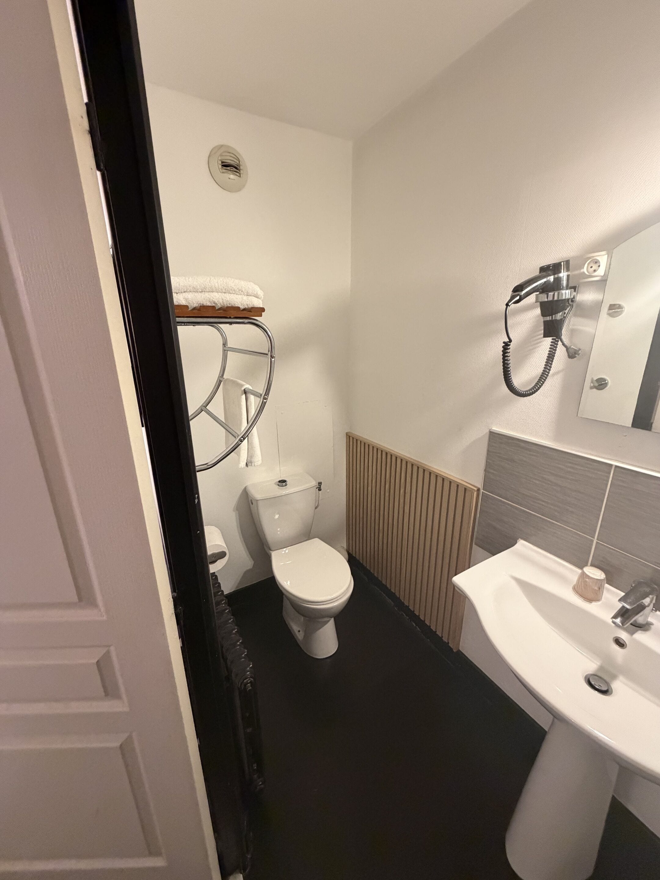 Een kleine badkamer met toilet, wastafel en handdoekhouder.