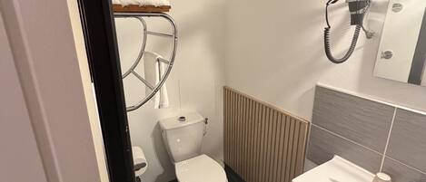A compact bathroom with a toilet, a sink, and a towel rack.