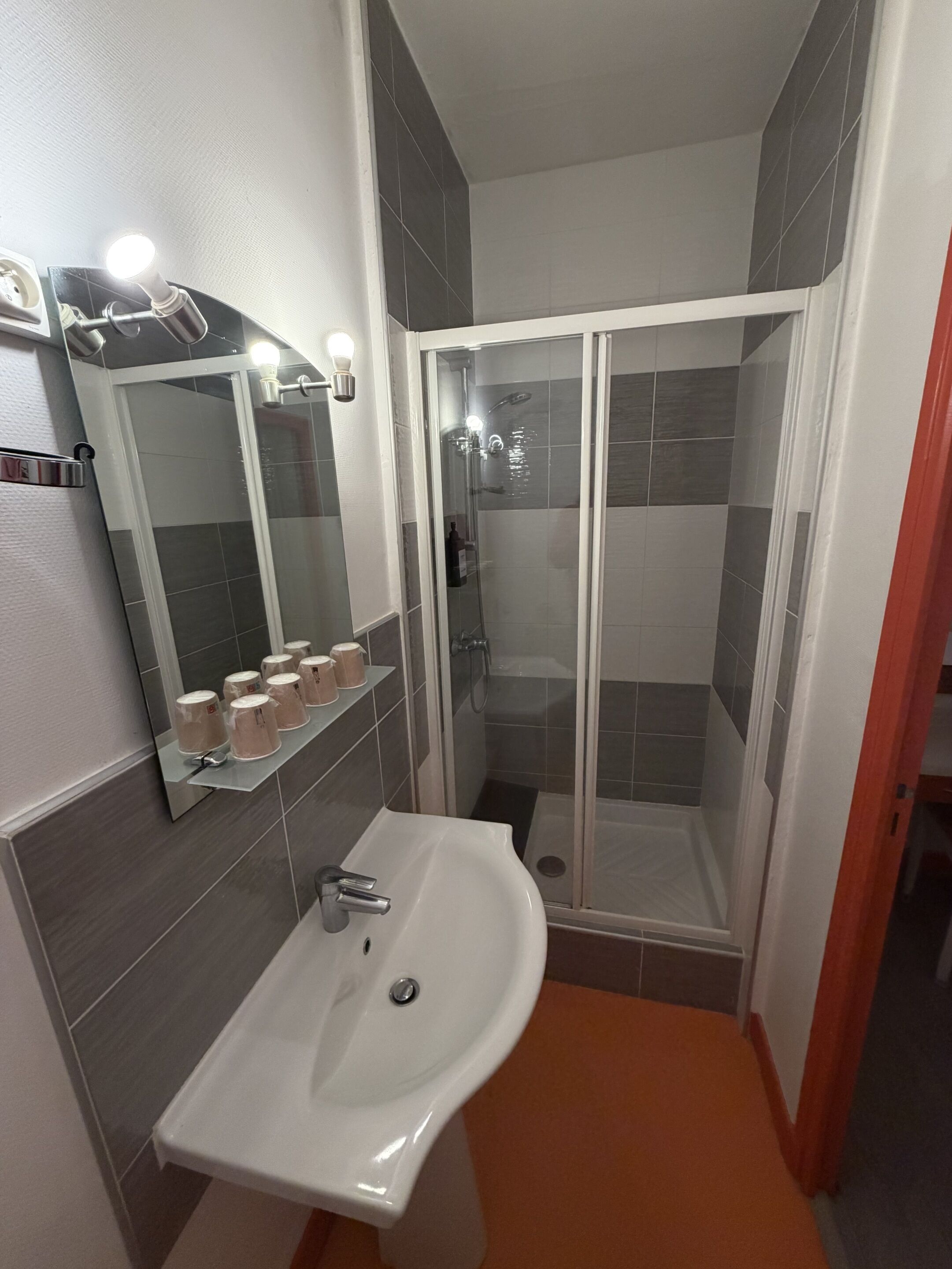 A bathroom with a sink, mirror, and shower.