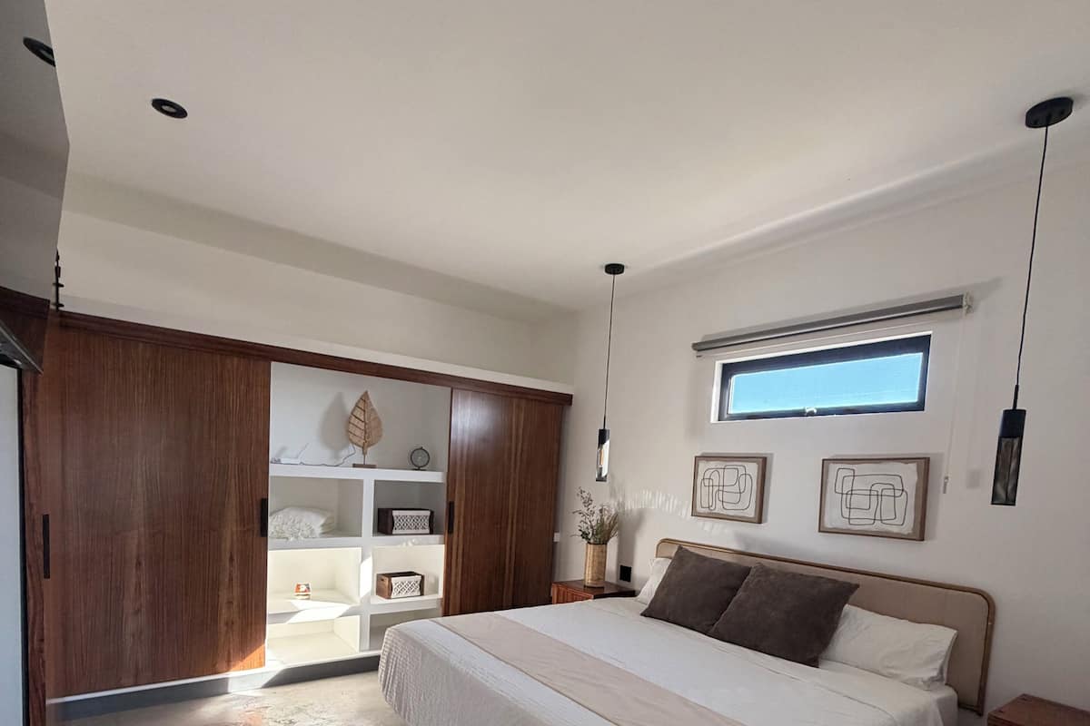 Un dormitorio con una cama grande, armario de madera y un tragaluz.