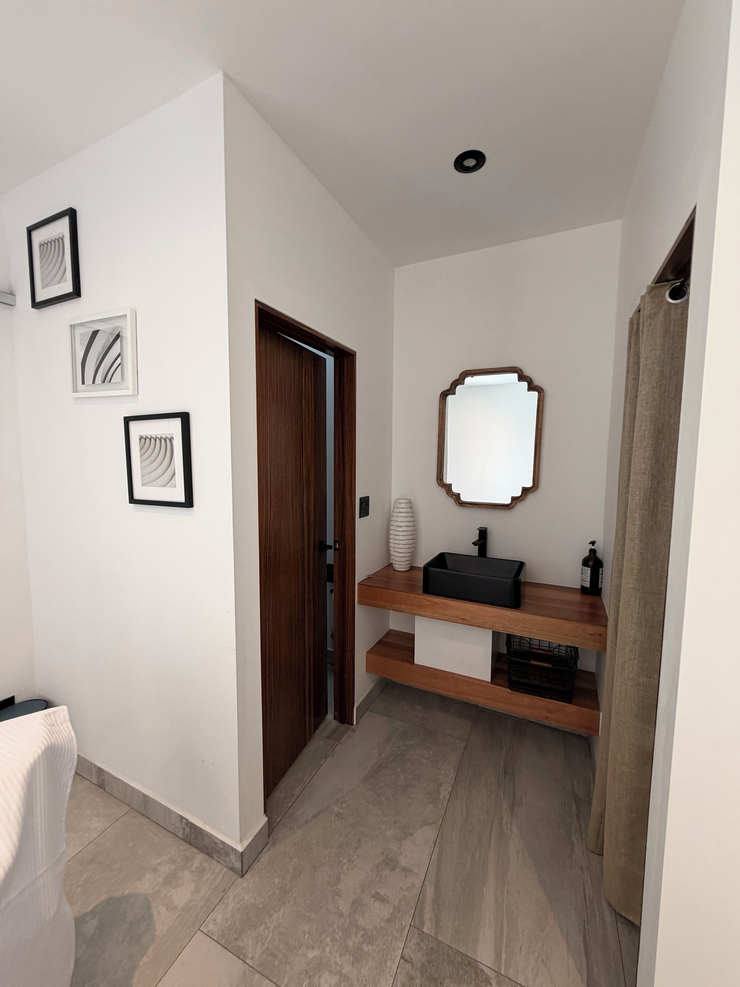 Een moderne badkamer met een houten wastafelmeubel, een spiegel en lijstwerken aan de muur.