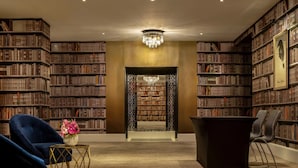 Une bibliothèque dotée d’étagères, d’un lustre et d’espaces aménagés pour s’asseoir.