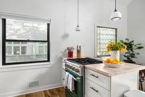 A kitchen with a stove, oven, and a window with a view of a house. - Inman Park Treetop Retreat – Walk to Beltline & Top Restaurants (Atlanta)