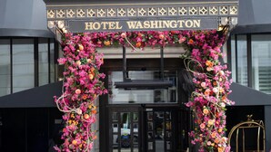 L’entrée d’un hôtel, sur laquelle on peut lire l’inscription « HÔTEL WASHINGTON », et qui est agrémentée de décorations florales.