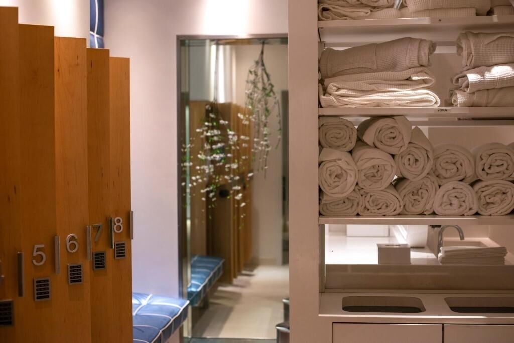 Ein Hotelbad mit Holzzahlzeichen, einem Waschbecken und ordentlich gestapelten Handtüchern.