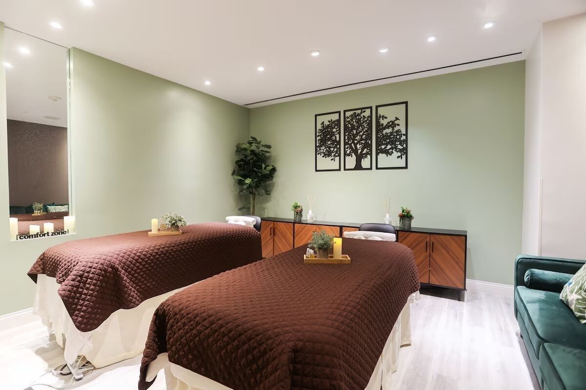 Une chambre avec deux lits, un canapé vert, une armoire en bois et des œuvres d’art murales.