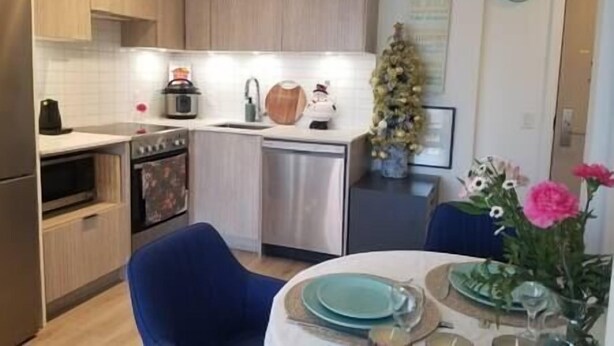 Une cuisine compacte dotée d’appareils électroménagers modernes, un coin repas avec une table dressée pour deux personnes, et un sapin de Noël décoratif.