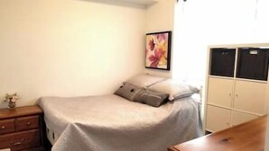 Une chambre à coucher comprenant un lit, une table de chevet, une commode et une armoire.