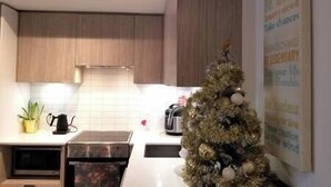 Une cuisine moderne avec des meubles en bois, un four à micro-ondes, une bouilloire et un petit sapin de Noël.