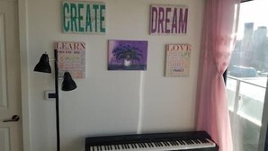 Une pièce avec un piano, des affiches inspirantes et une lampe.