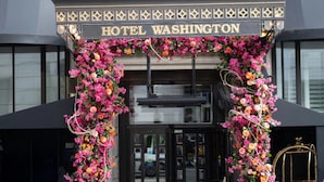 Entrada de un hotel con un letrero que dice "HOTEL WASHINGTON", decorada con adornos florales.