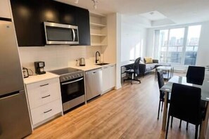Una cocina moderna con microondas, estufa y lavavajillas. Hay un comedor con mesa y sillas.