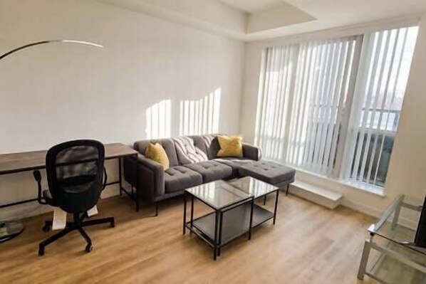 Una sala moderna con un sofá modular, una mesa de centro de vidrio y un escritorio con una silla.