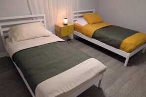 Une chambre avec deux lits simples, chacun ayant une décoration aux couleurs différentes.