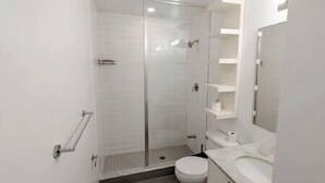 A modern bathroom with a glass shower enclosure, a toilet, and a vanity with a mirror.