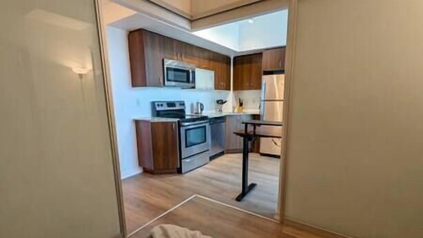A modern kitchen with wooden cabinets, a microwave, an oven, and a small dining table.