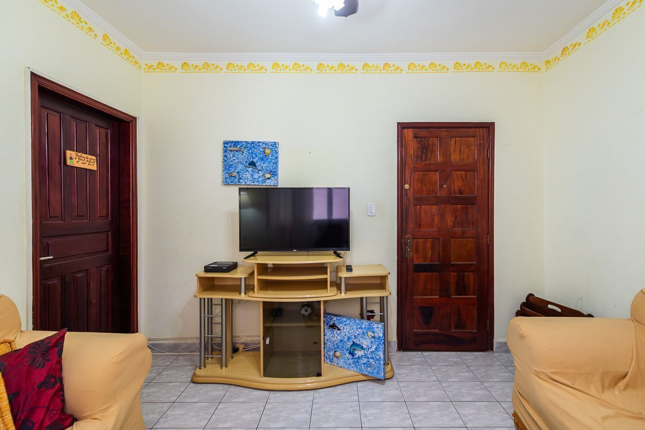 A living room with a TV on a wooden stand, two doors, and a sofa.
