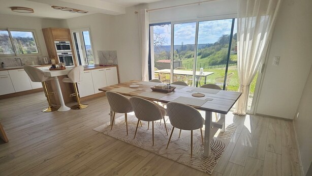 Una cocina moderna con comedor, ventanas amplias y vistas al campo.