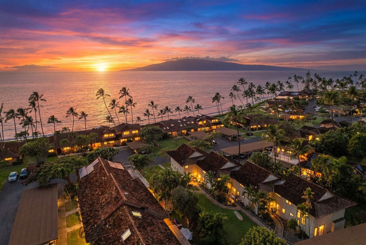 A resort with multiple bungalow-style buildings, a beachfront view, and a sunset over the ocean.