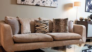 A beige sofa with multiple cushions, a glass coffee table, and a floor lamp.