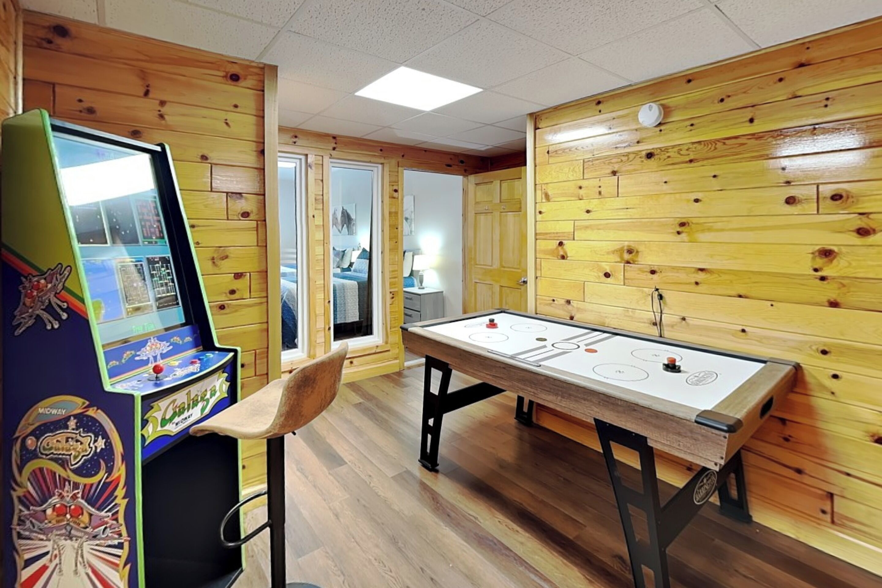 A room with wooden walls, a foosball table, and a video game machine.