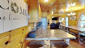 A cozy cabin interior with a kitchen, bar area, and seating space. - Bluff Mountain Vista (Sevierville)