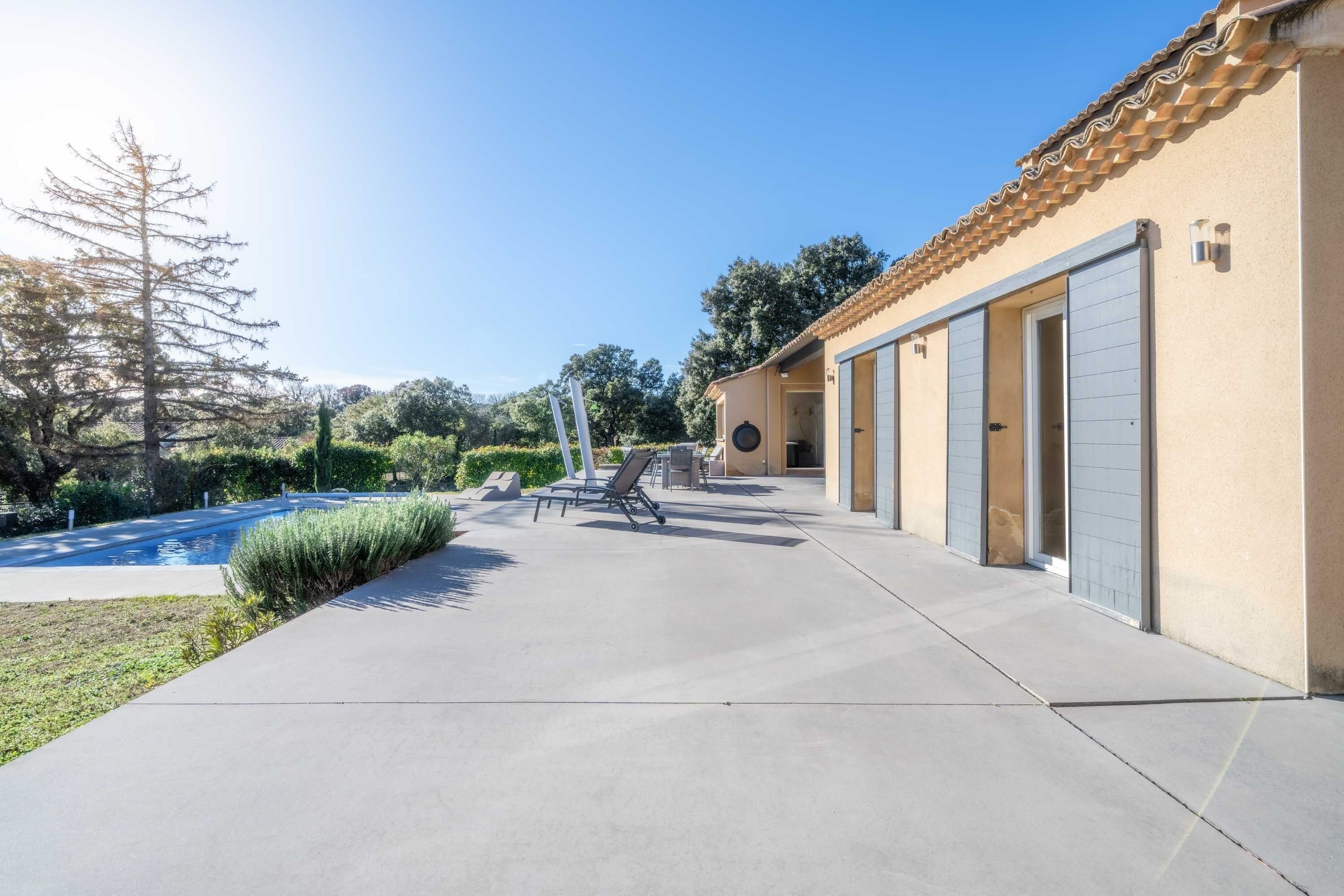 A building with a concrete patio, a swimming pool, and a door with a garage.