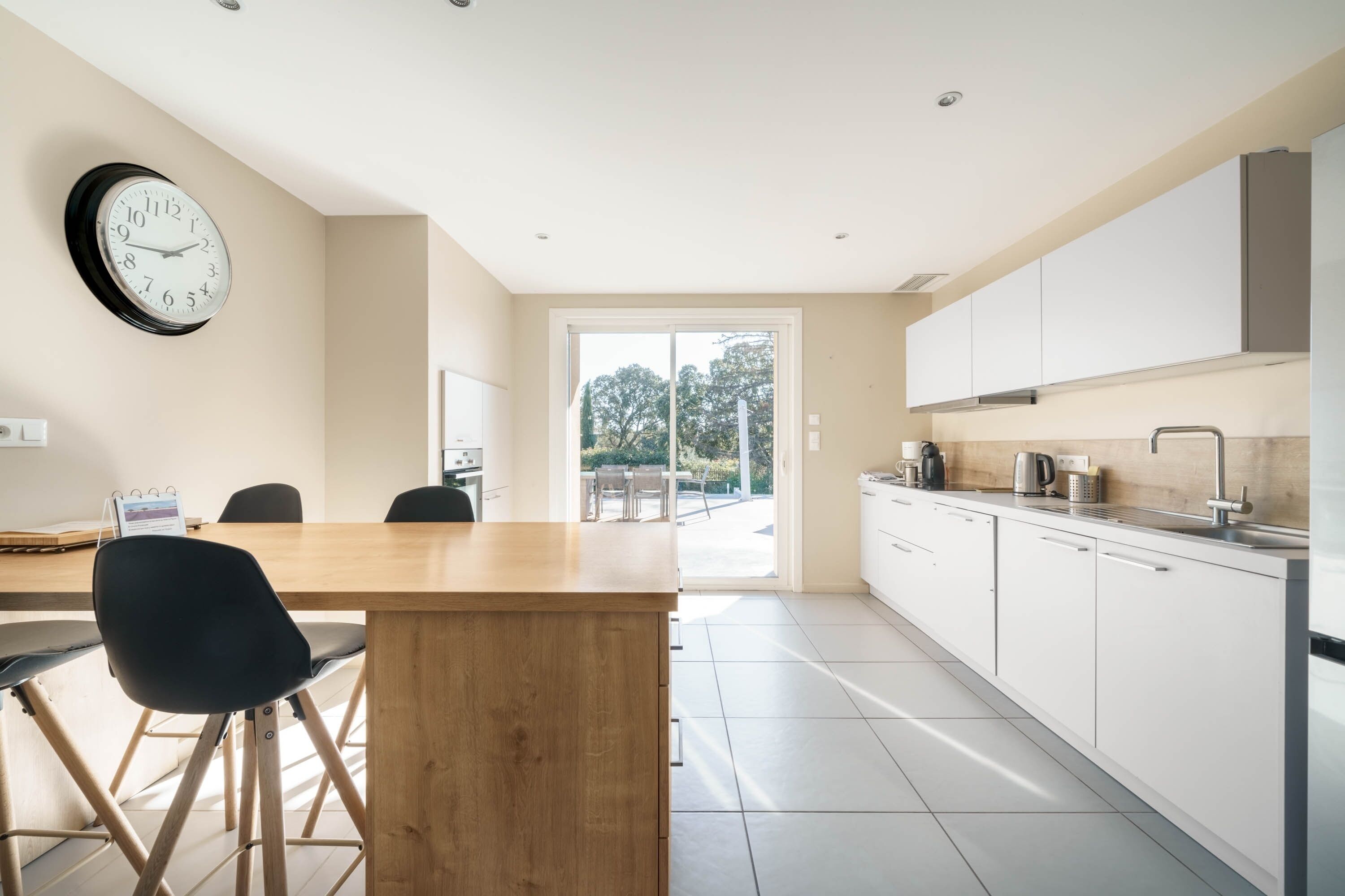 Una cocina moderna con armarios blancos, una mesa de comedor de madera y una silla negra.