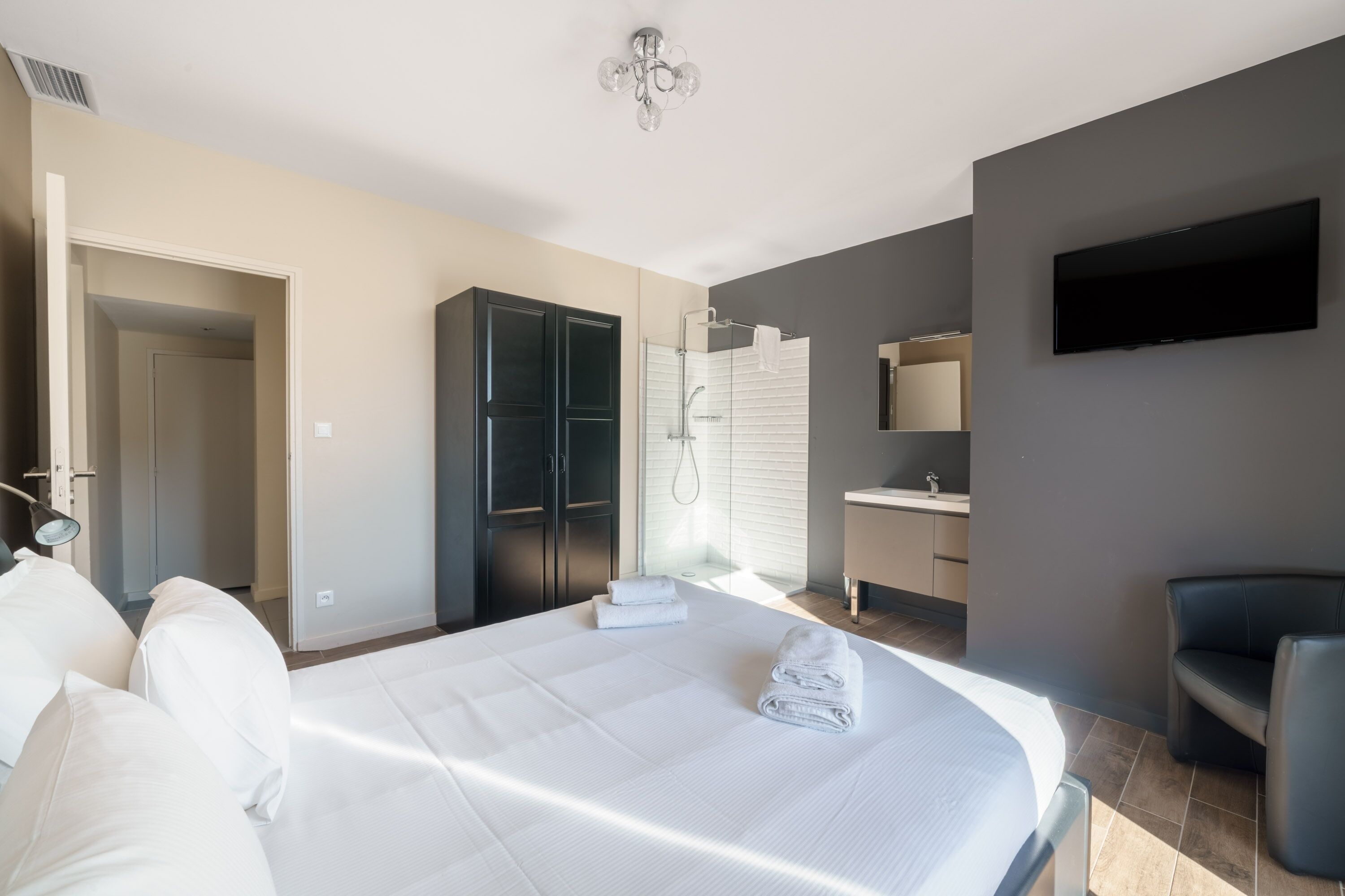 A hotel room with a large bed, a shower, a TV, and a seating area.