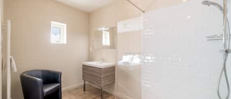 Een moderne badkamer met een douche, een wastafel en een zithoek.