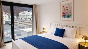 Une chambre d’hôtel avec un lit, une vue sur la ville et un tableau au mur.