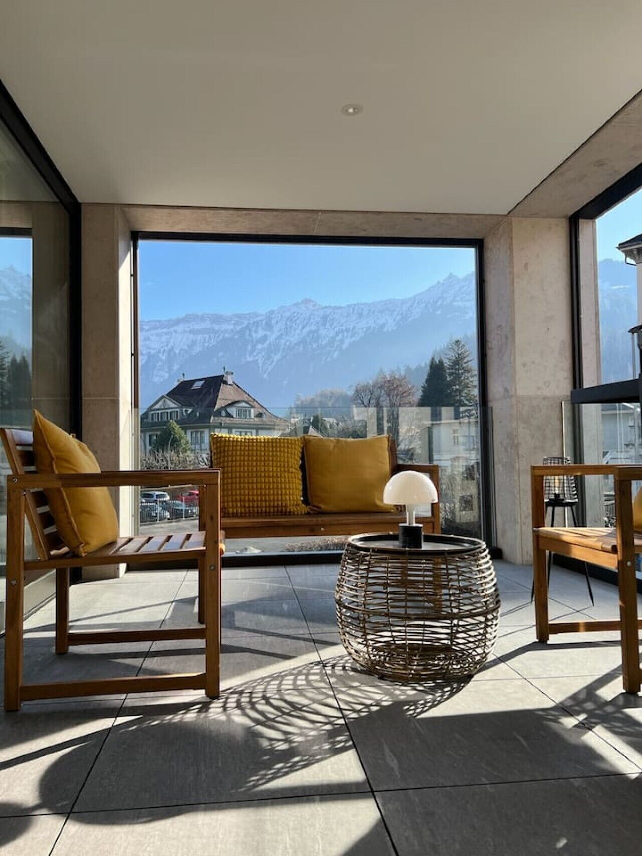 Ein Balkon mit einer Couch, Stühlen und einer Lampe, mit Blick auf eine Berglandschaft.