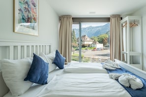 Ein Hotelzimmer mit zwei Betten, einem Fenster mit Vorhängen, einem Heizkörper und einem Bild an der Wand.