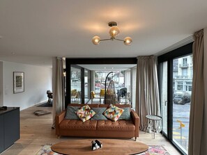 Ein modernes Wohnzimmer mit einer Ledersofa, einem Holztisch und einer Hängelampe.